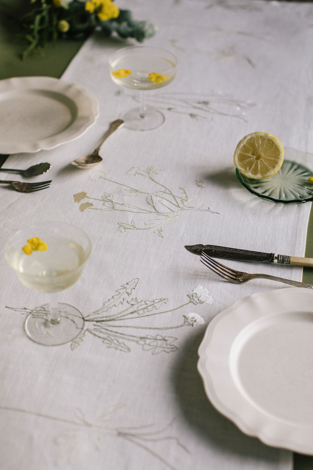 White Irish linen table runner with embroidered drawings of different plants with roots 