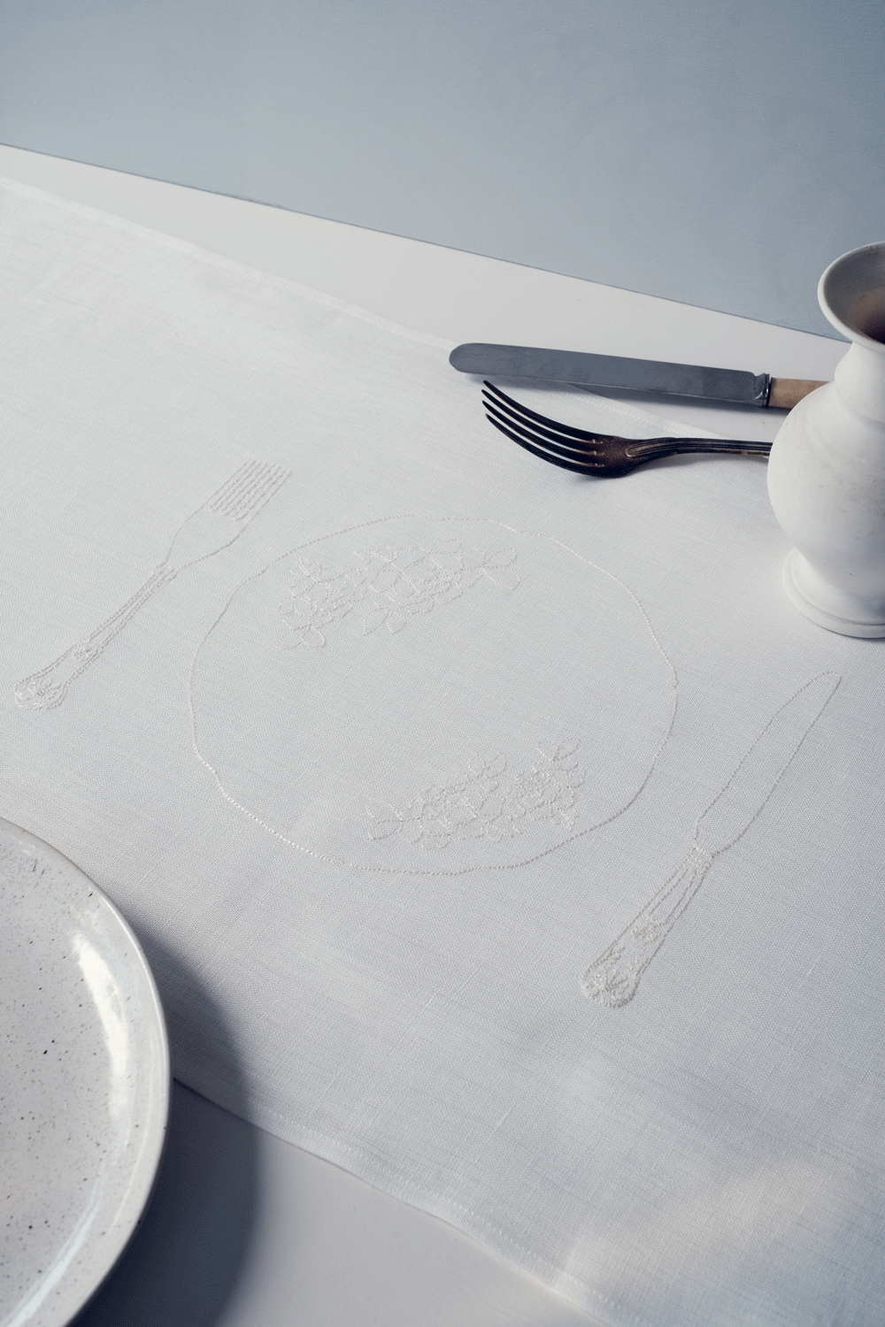 Irish linen table runner with white, tonal embroidery of a knife, fork and plate 